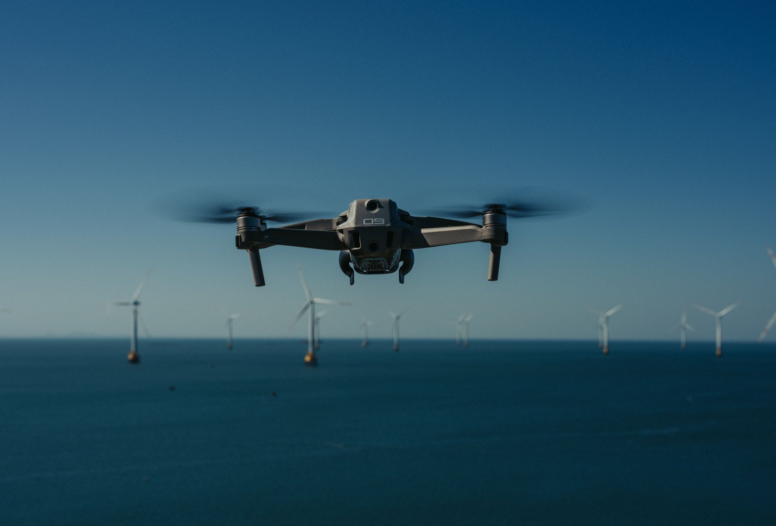 A drone above the sea near offshore wind turbines