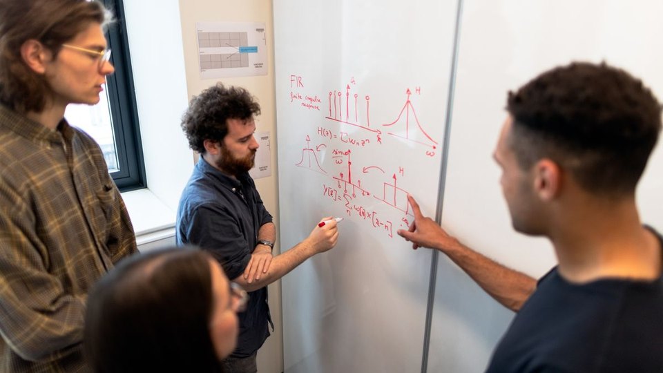 Engineers discussing calculations on a whiteboard