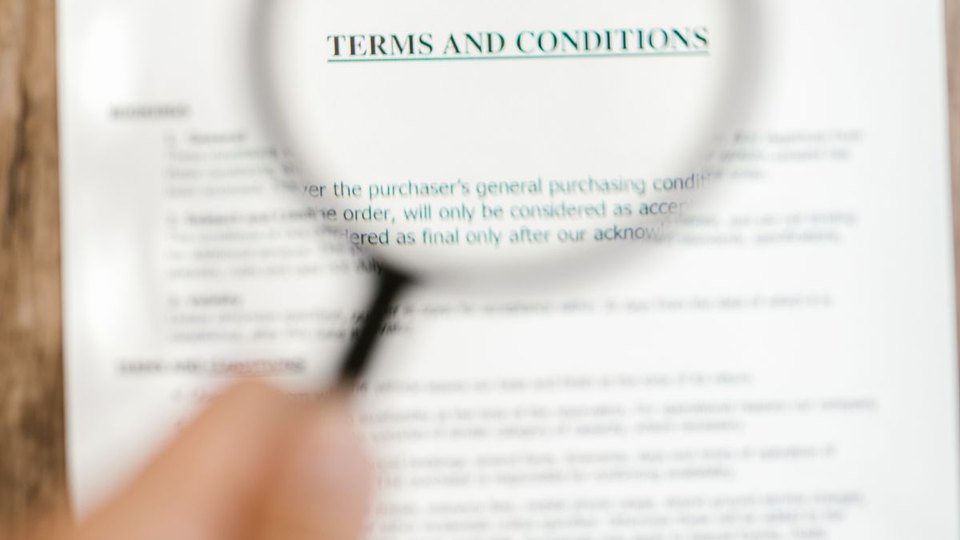 Magnifying glass examining a terms and conditions document