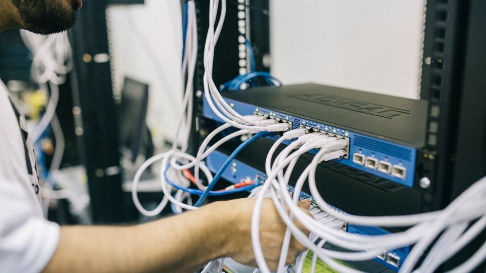 Hands configuring network connections in a server rack