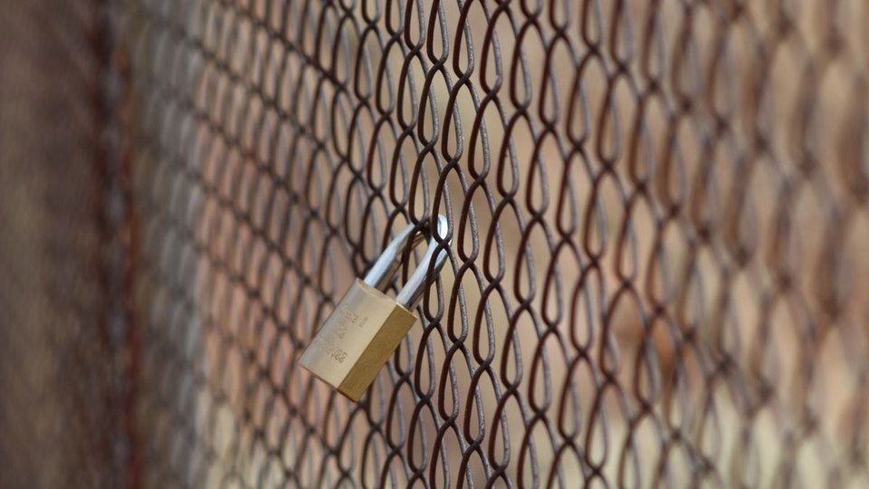 Metal padlock securing a mesh fence