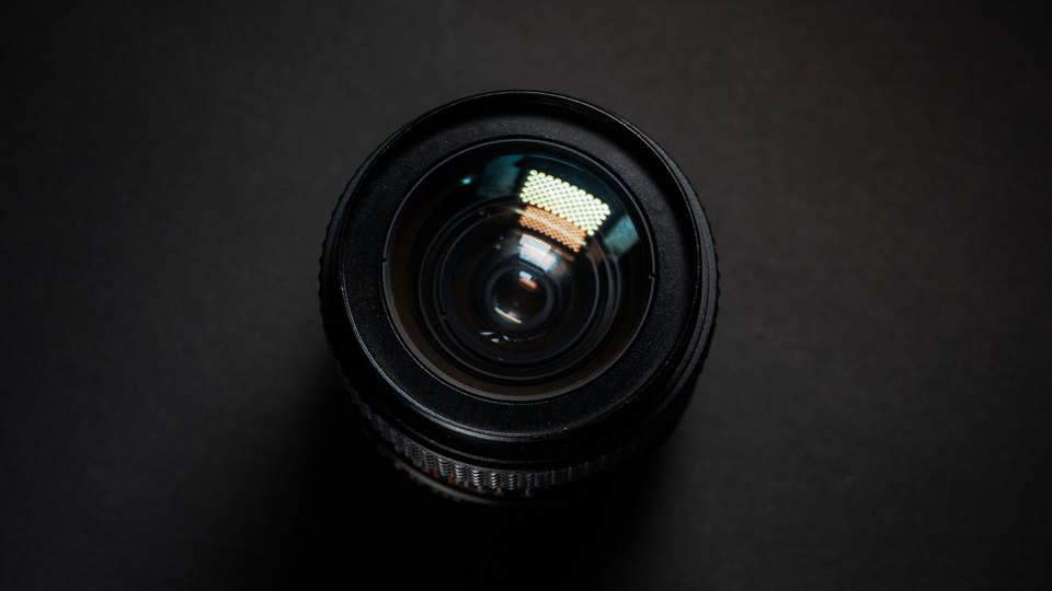 Close-up of an optical camera lens against a dark background